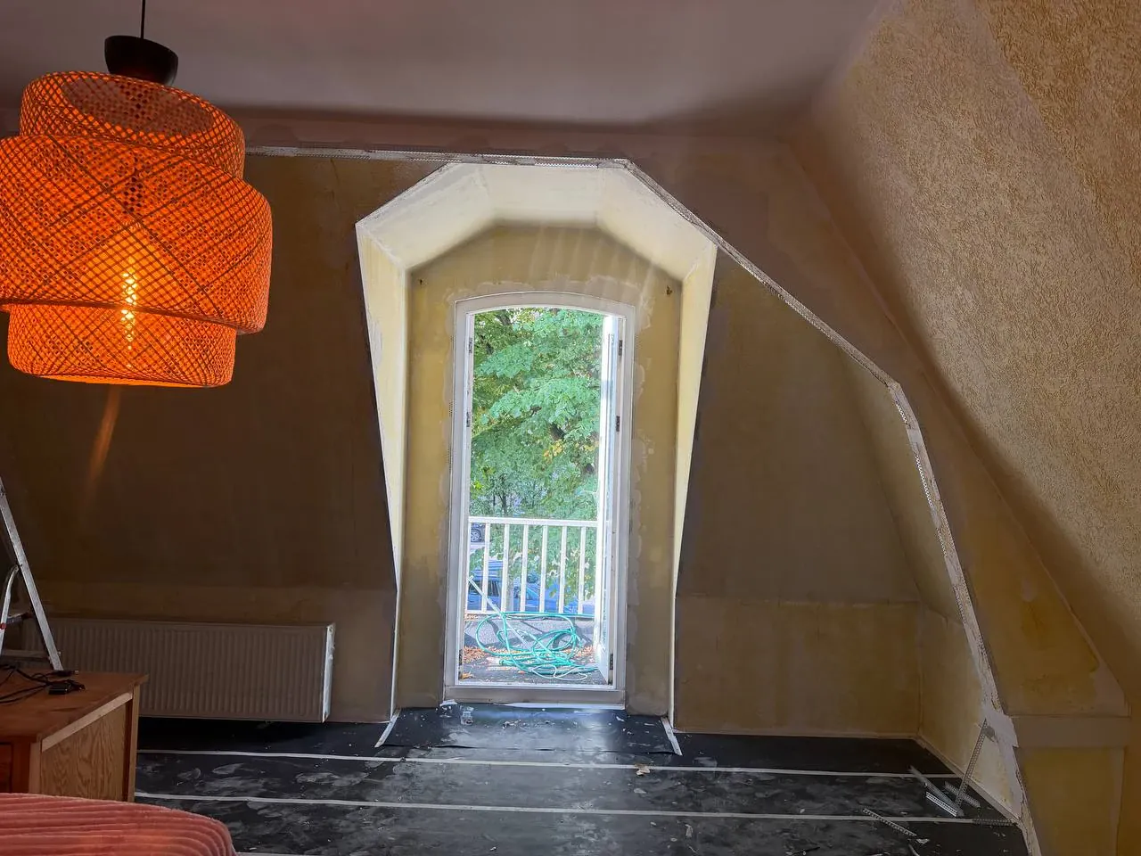 Zolderkamer met dakkapel en balkondeur vóór het stucwerk, met oude structuurwanden